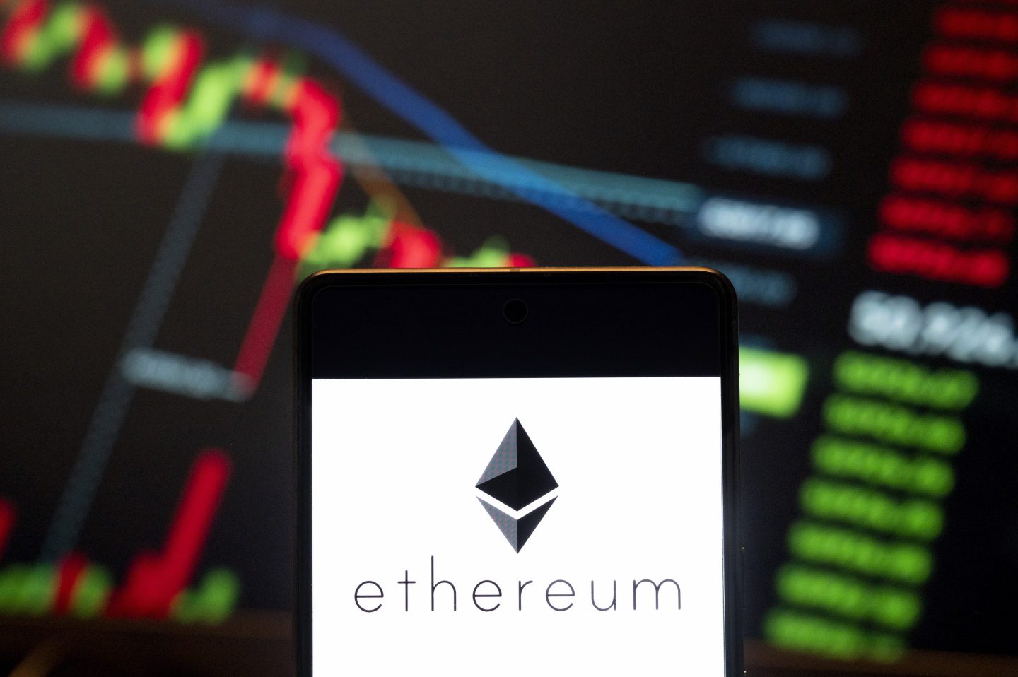 CHINA &#8211; 2024/06/21: In this photo illustration, the cryptocurrency generated by the Ethereum (Ether, ETH) logo seen displayed on a smartphone with an economic stock exchange index graph in the background. (Photo Illustration by Budrul Chukrut/SOPA Images/LightRocket via Getty Images)