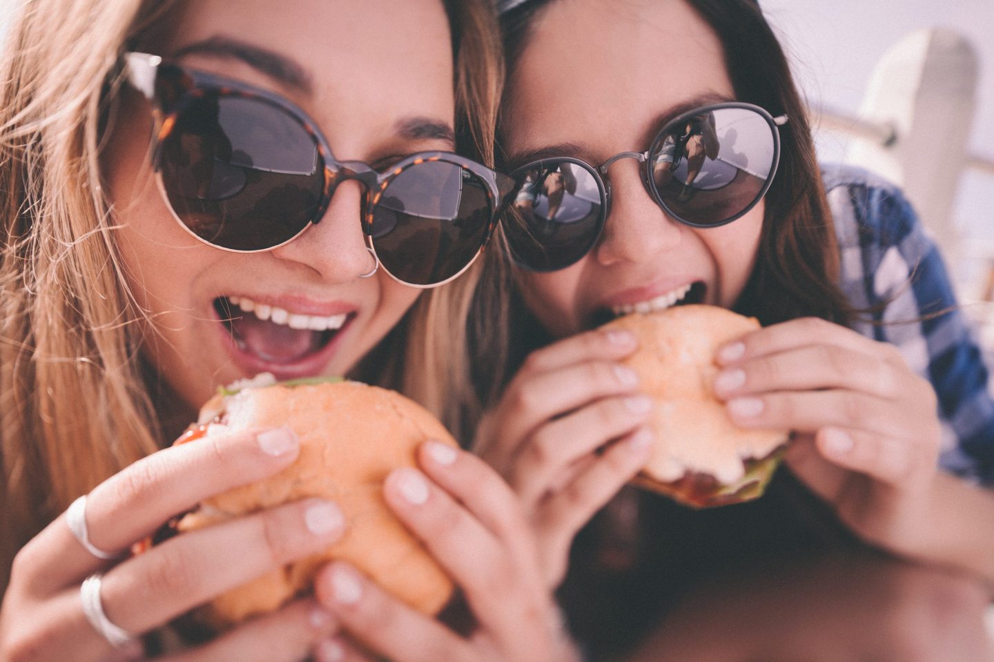 closeup of teen girls eating burgers and wearing sunglasses