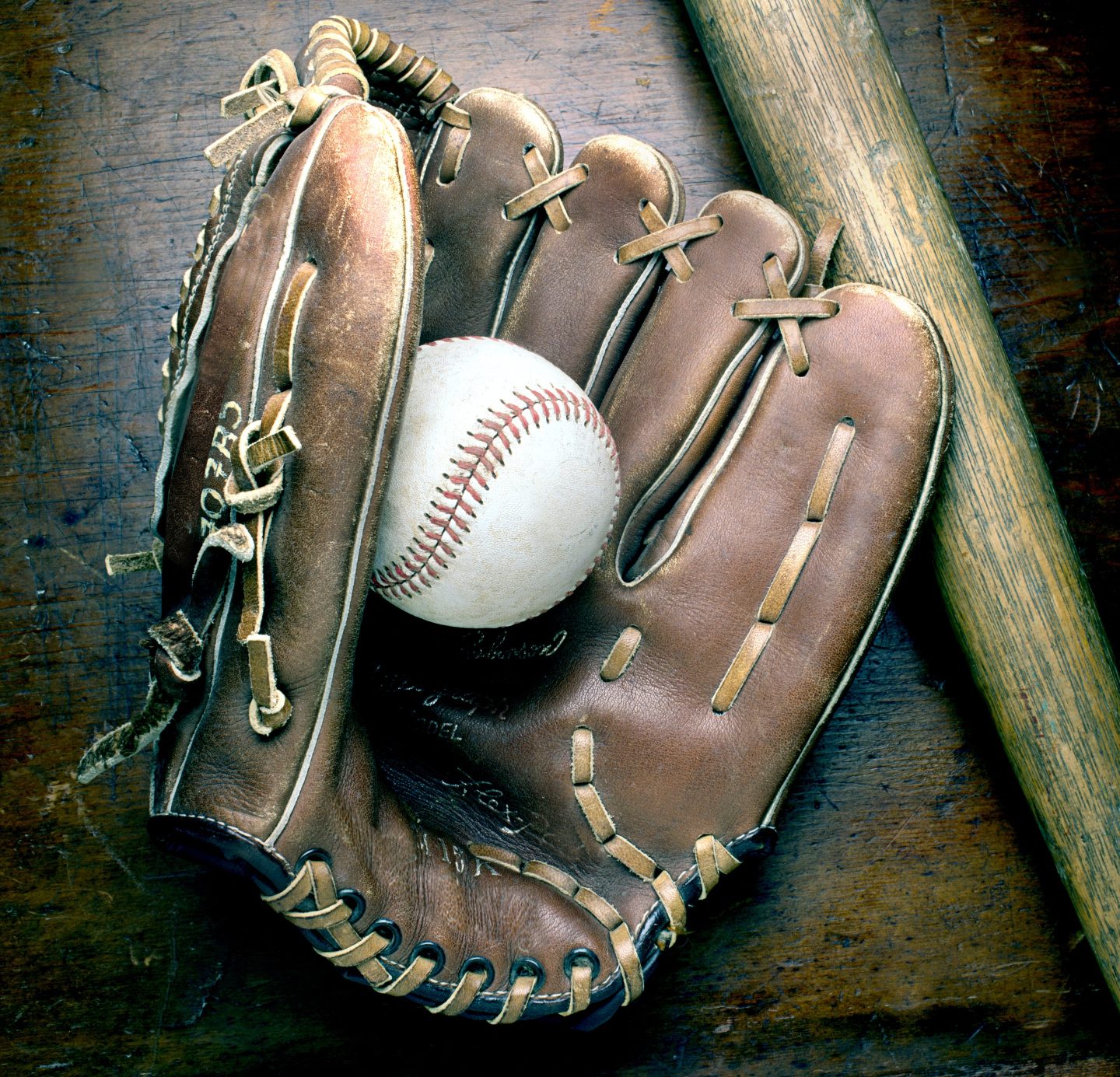 baseball inside a glove and a bat on the side