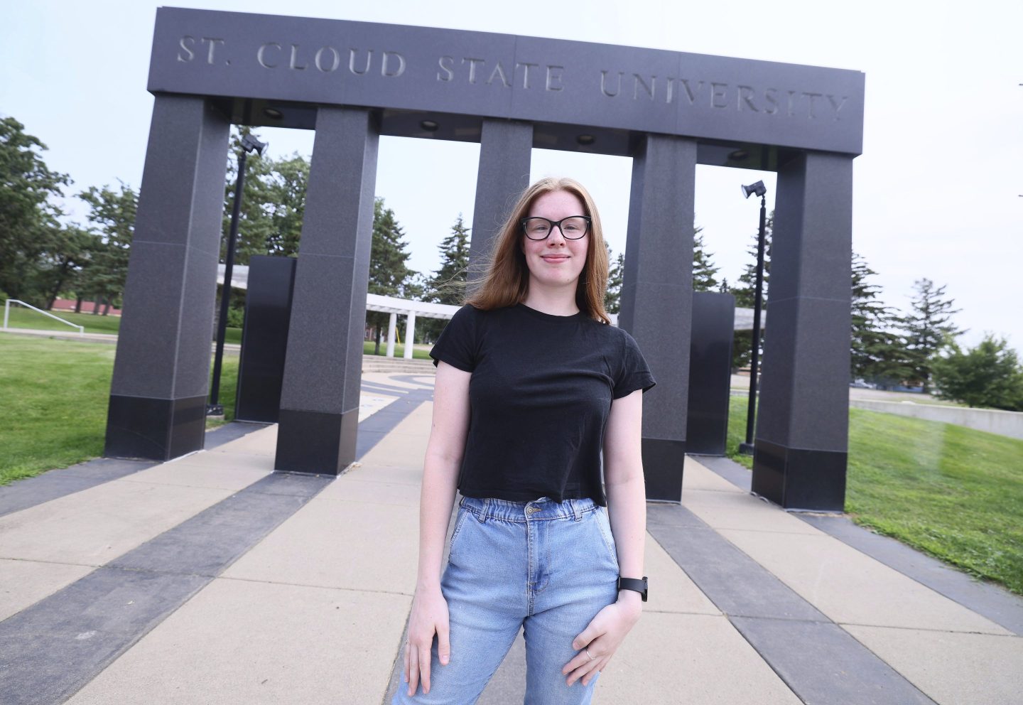 student stands in front of school