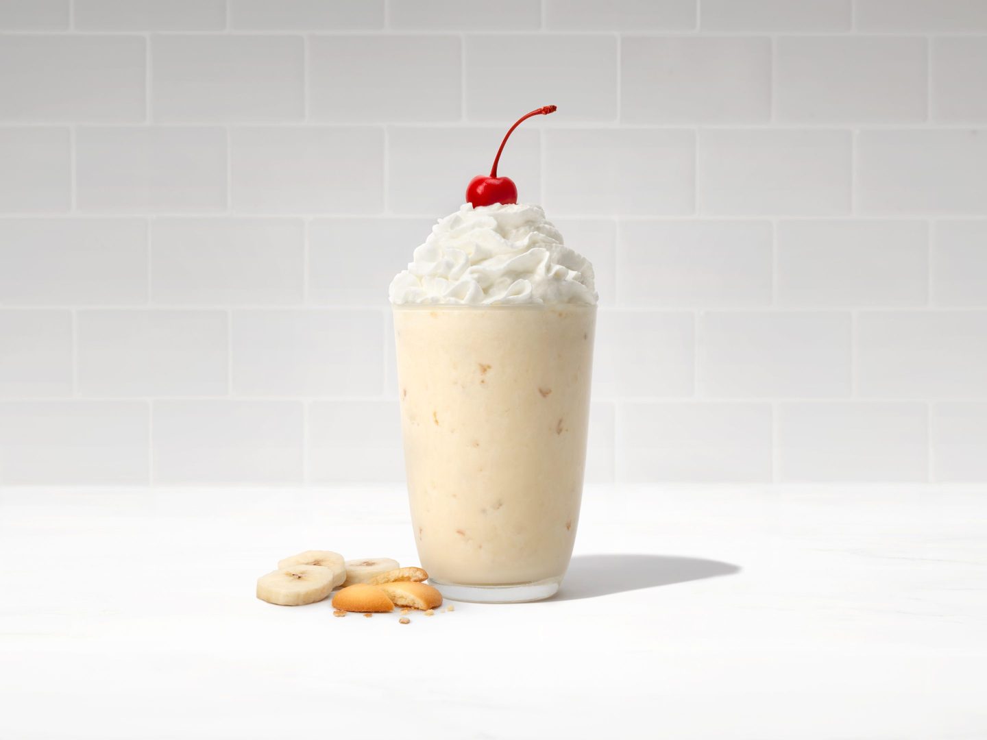 millkshake in a glass topped with whipped cream and a cherry