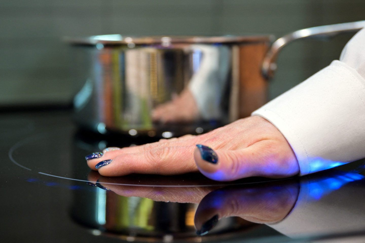 A woman inexplicably putting her hand on an active oven range