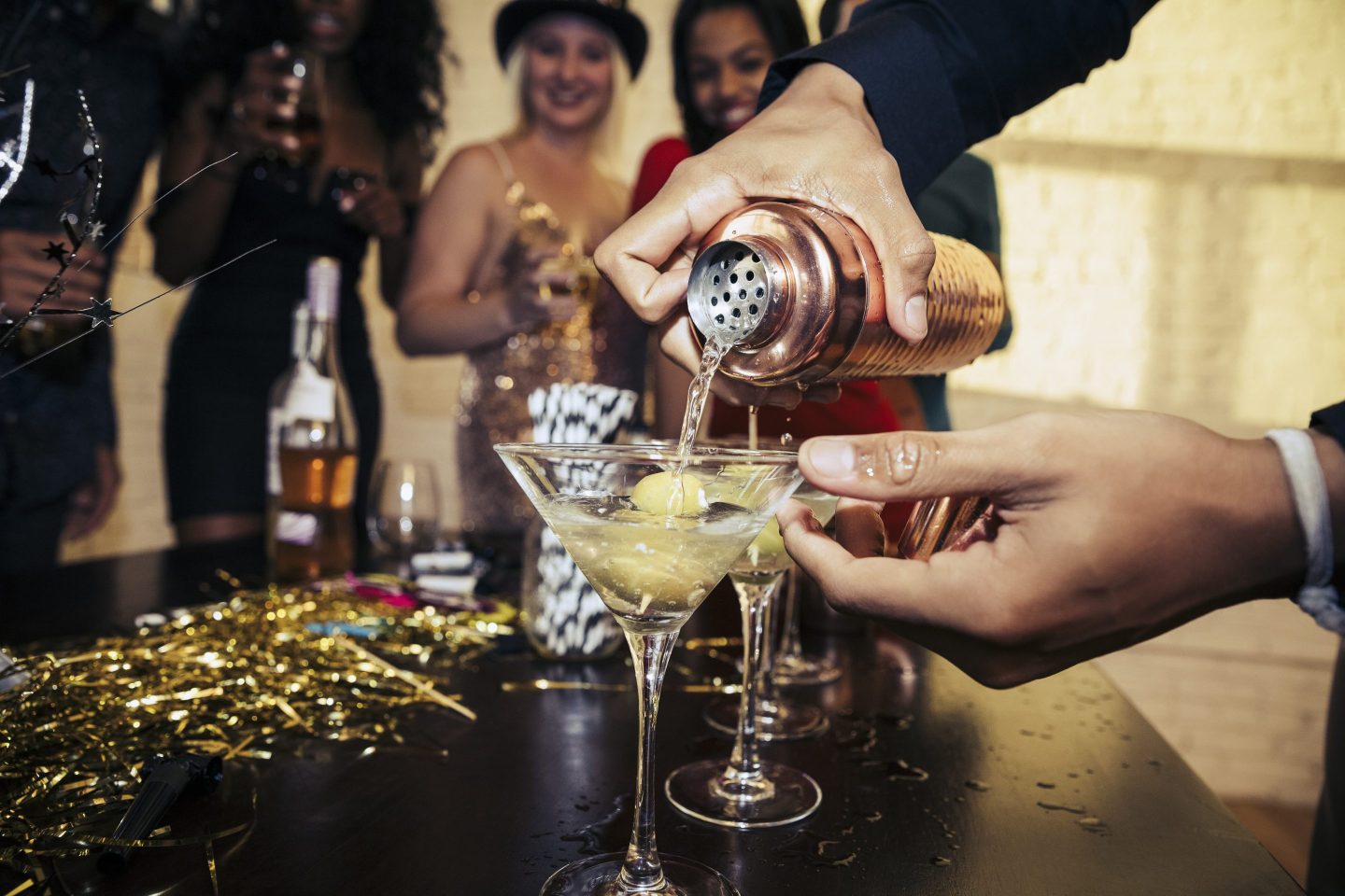 Close-up of hands pouring a martini out of a cocktail shaker