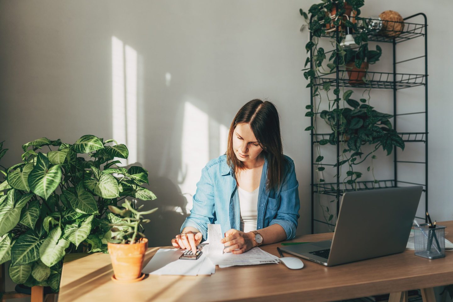 Top view close up woman calculating bills, money, loan or rent payments, using laptop, online banking service, sitting at table, female holding receipt, planning budget, managing expenses, finances