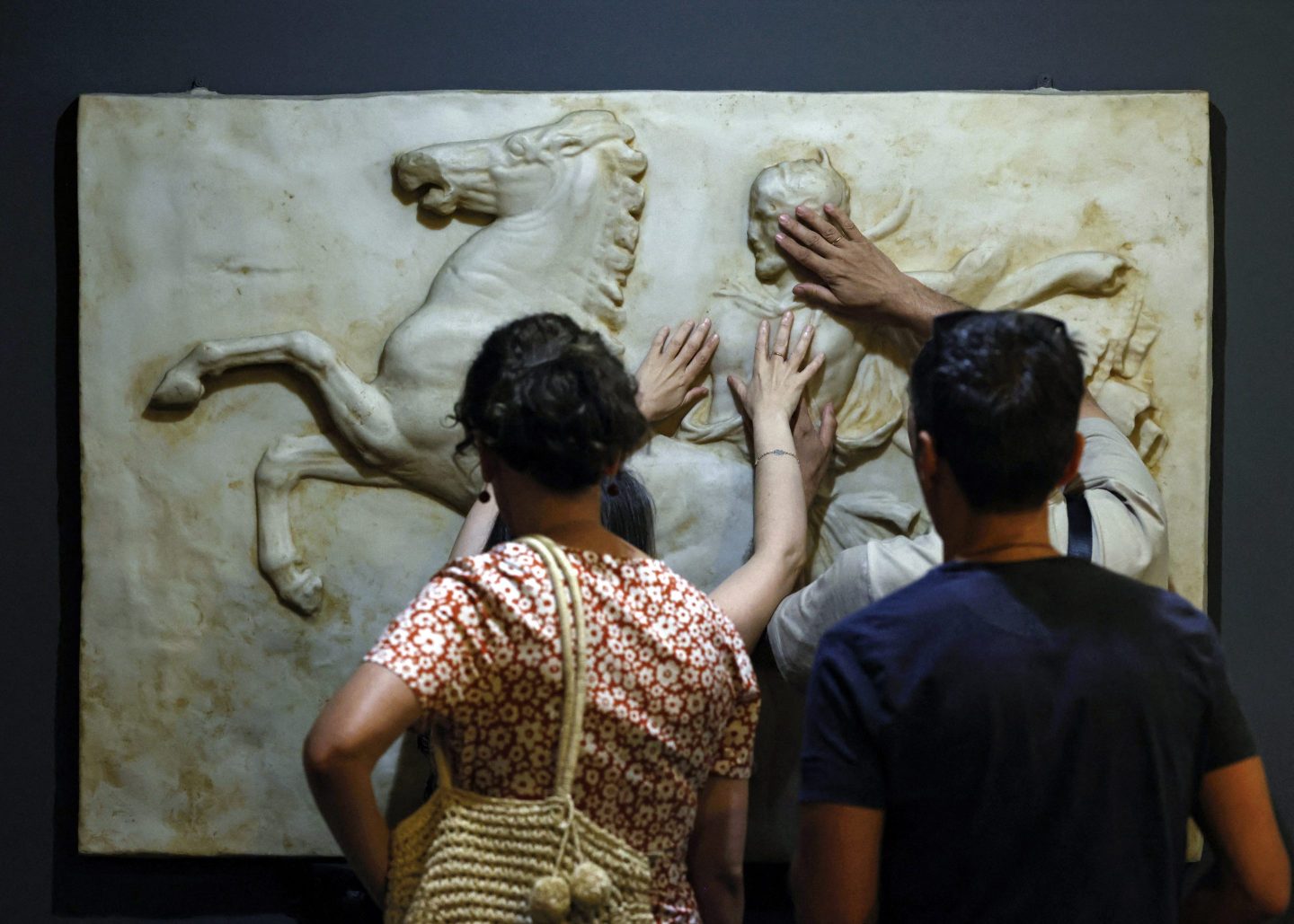 Visually impaired visitors touch with their hands a model depicting reliefs of the Parthenon at Typhlological Museum in Madrid on August 6, 2024. The Madrid Typhlological Museum -- from the Greek "tuphlos" meaning blind -- houses 37 reproductions of global monuments that are listed as world heritage sites. It was set up in 1992 by ONCE, Spain's powerful national organisation for the blind which has 71,000 members. Made of wood, stone, metal or resin, the models are accessible to all visitors -- whether blind, sighted or partially sighted -- giving them a hands-on, sensory experience of the architecture. (Photo by OSCAR DEL POZO / AFP) (Photo by OSCAR DEL POZO/AFP via Getty Images)