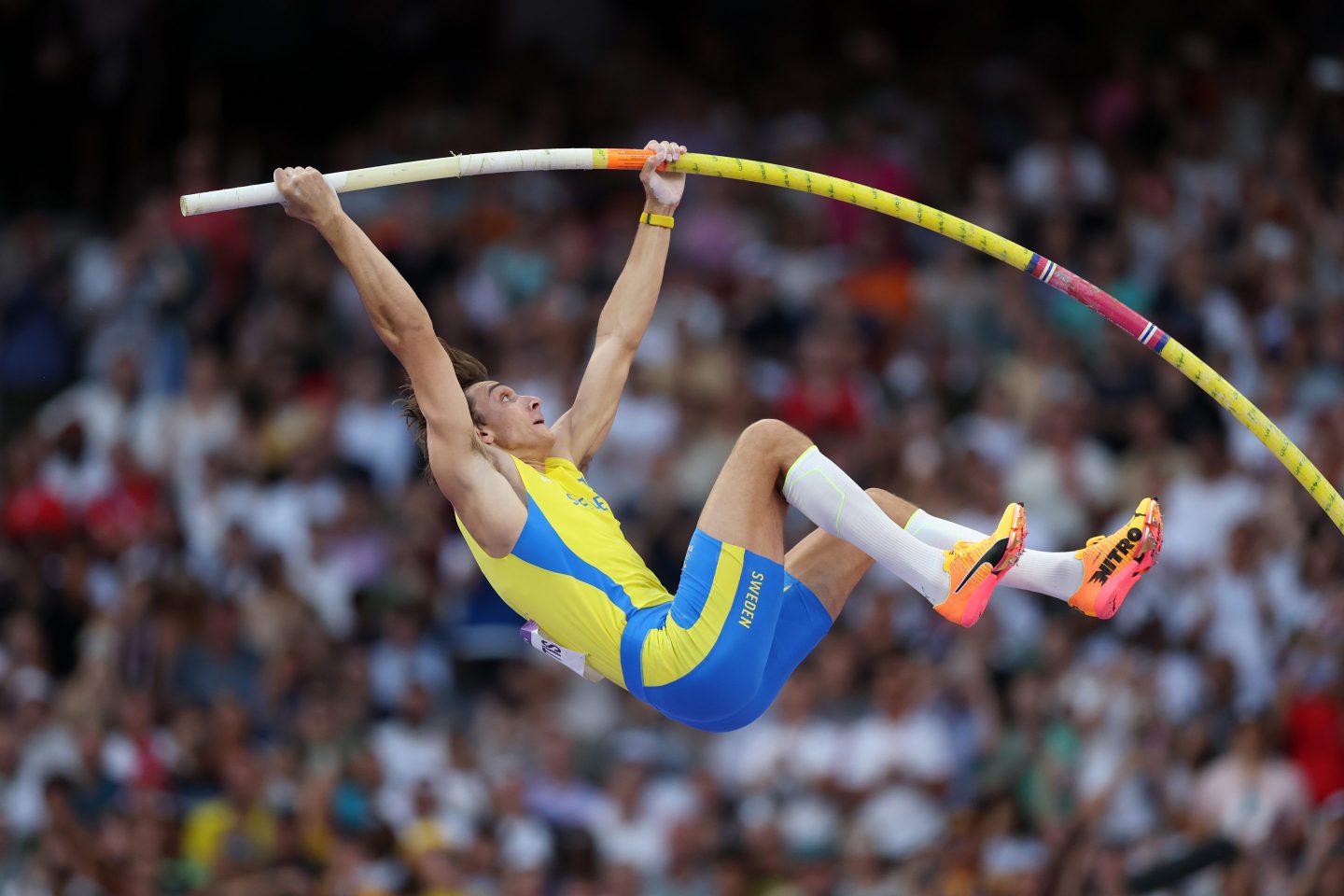 A male pole vaulter launching into the air at the Olympics