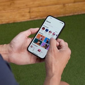 a man viewing the ClassPass fitness app on a smartphone screen, searching for different workouts