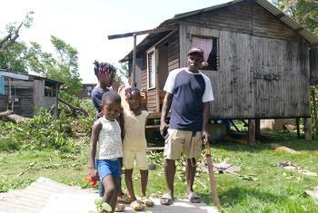 A family stands outside their home damaged by Hurricane Beryl in St. Andrews, Grenada.