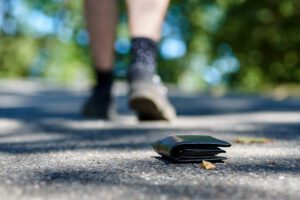 the sidewalk and legs of a man who lost a black leather wallet while walking