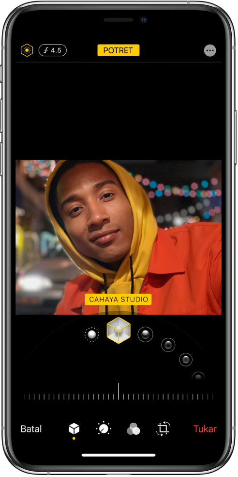 Skrin Edit untuk foto mod Potret. Di bahagian kiri atas skrin ialah butang Keamatan Pencahayaan dan butang Pelarasan Kedalaman. Di bahagian tengah atas skrin ialah butang Potret aktif dan di bahagian kanan atas ialah butang Pemalam. Foto berada di bahagian tengah skrin dan di bawah foto ialah gelangsar untuk memilih Kesan Cahaya Potret dan di bawah ialah gelangsar untuk melaraskan nilai. Di bawah gelangsar skrin, dari kiri ke kanan ialah butang Batal, Potret, Laras, Tapis, Pangkas dan Kembali.