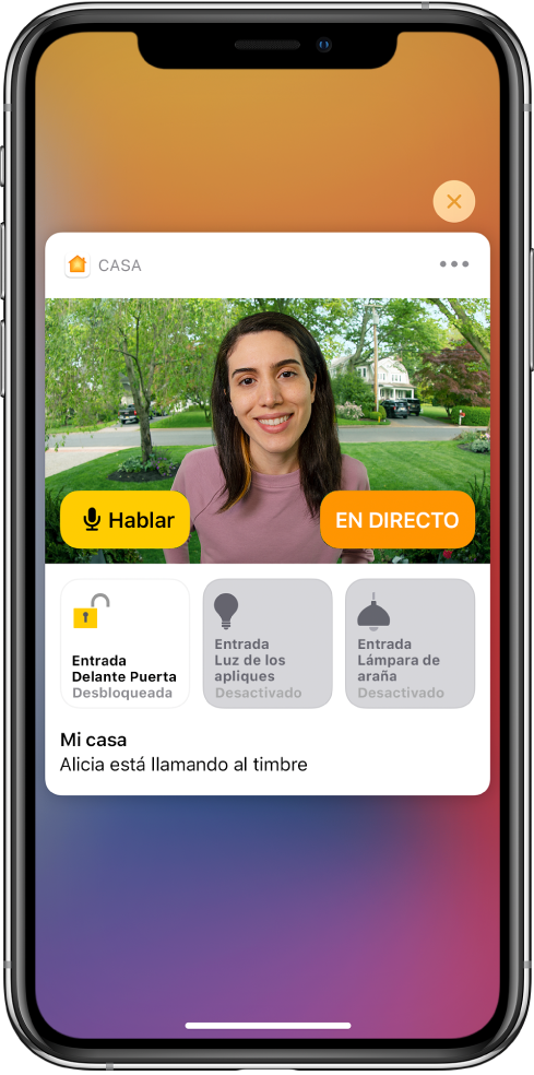 En la pantalla del iPhone hay una de notificación de Casa. Se muestra la imagen de una persona en la puerta principal con un botón para hablar a la izquierda. Debajo están los botones de accesorios para la puerta principal y las luces de la entrada. Las palabras “Aurora está llamando al timbre”. En la parte superior derecha de la notificación está el botón Cerrar.