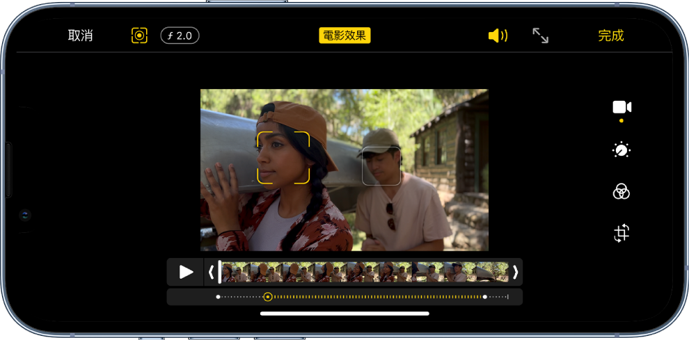 橫向的「電影效果」影片中的「編輯」畫面。在螢幕左上方是「取消」按鈕、「電影效果手動」按鈕及「景深調整」按鈕。在螢幕的中間上方,已選取「電影效果」按鈕。在螢幕右上方是「音量」按鈕、「進入全螢幕」按鈕及「完成」按鈕。影片位於螢幕中央,焦點對象周圍出現方框。影片下方是影格檢視器,顯示影片中主體焦點變更的點。編輯工具位於螢幕的右側,從上至下為:「影片」、「調整顏色」、「濾鏡」和「裁剪」。