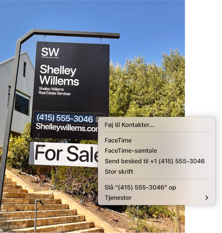 Et foto af en ejendomsmæglers til salg-skilt, der viser mæglerens telefonnummer valgt som livetekst og en menu med muligheder for at føje telefonnummeret til Kontakter, ringe til nummeret, starte et FaceTime-opkald, sende en tekstbesked m.m.