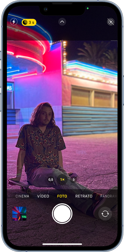 Tela da Câmera no modo Foto. Botões do flash e do modo Noite aparecem no canto superior esquerdo da tela. O flash está desativado e o modo Noite está ativado. O botão Controles da Câmera está na parte superior central e o botão Live Photo está no canto superior direito. Na parte inferior da tela estão, da esquerda para a direita, o botão Visualizador de Foto e Vídeo, o botão Tirar Foto e o botão Seletor de Câmera Traseira.