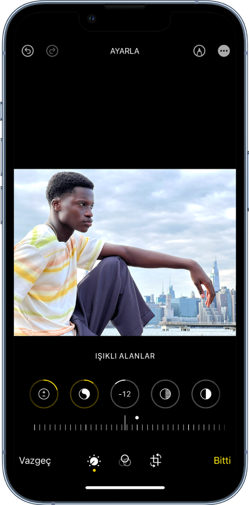 Ortadaki bir fotoğraf ile Düzenle ekranı. Fotoğrafın altında İyileştirme, Pozlama, Parıldama ve Işıklı Alanlar için düzenleme düğmeleri var. Parlaklık seçilidir. Düzenleme düğmelerinin altında Parlaklık seviyesinin ayarlanması için bir sürgü var. Sürgünün altında, soldan sağa doğru Ayarla, Filtreler, Kırp ve Bitti düğmeleri bulunuyor. İşaretle düğmesi sağ üst köşede.