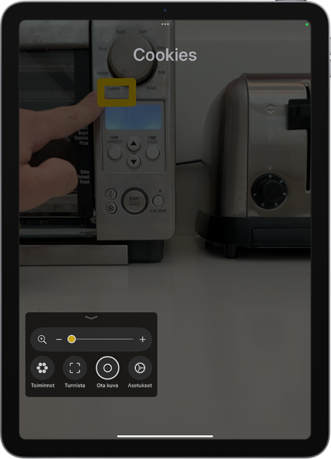 Suurennuslasi-appi tunnistaa sormen, joka osoittaa tekstiä keittiön laitteessa.