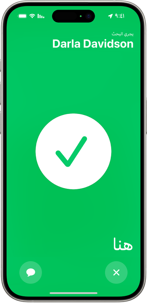 شاشة iPhone خضراء وفي وسطها علامة اختيار كبيرة. اسم الشخص الذي يجري تحديد موقعه يظهر في الزاوية العلوية اليمنى، وكلمة "هنا" في الزاوية السفلية اليمنى، مما يشير إلى أن اللقاء كان ناجحًا.