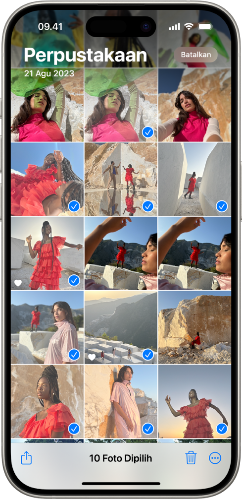 Layar iPhone dipenuhi dengan grid foto, beberapa di antaranya dipilih. Di bagian bawah layar terdapat tombol Bagikan, Hapus, dan Lainnya.