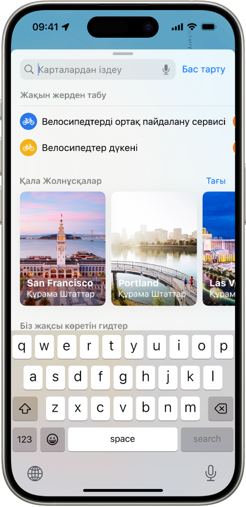 Іздеу өрісі, жақын жердегі қызметтердің санаттары мен қала бойынша жолнұсқаларды көрсетіп тұрған «Карталар» қолданбасы. Экранның төменгі жағында iPhone экран пернетақтасы көрсетілген.