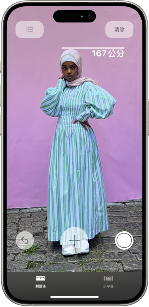 在「測距儀」App 中測量人物的身高,測量的高度在人物的頭頂顯示。正使用靠近右下角的「拍照」按鈕拍攝測量照片。綠色的「相機使用中」指示器顯示於最上方。