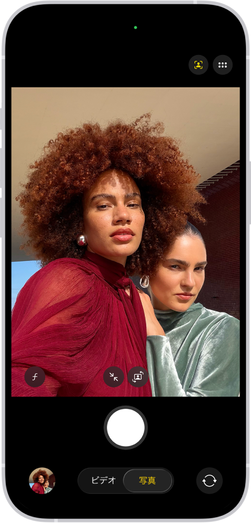 「写真」モードの「カメラ」画面。カメラの枠内で、被写体がセルフィーを撮っています。