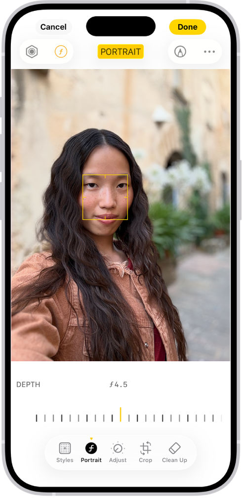 Het bewerkingsscherm in de Foto's-app, met in het midden een portretfoto. Onder de foto staat een schuifknop om de instelling 'Diepteaanpassing' aan te passen. Onder de schuifknop staan van links naar rechts de knoppen 'Stijl', 'Portret', 'Pas aan', 'Filters', 'Snij bij' en 'Ruim op'. De knop 'Portret' is geselecteerd.