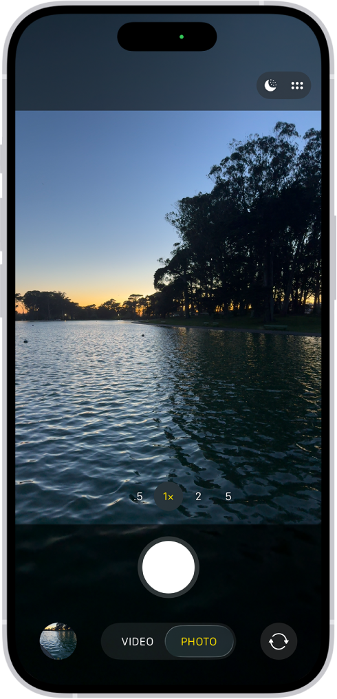 「相機」畫面中的「影相」模式。在觀景器中是晚間的場景。「夜間」和「相機控制項目」模式的按鈕顯示在螢幕右上角。螢幕底部由左至右為:「相片和影片檢視器」按鈕、「影相」和「攝影」模式,以及「相機選擇器後置鏡頭」按鈕。
