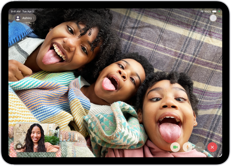 V teku je video klic FaceTime, ki prikazuje enega udeleženca v spodnjem levem kotu. Slika treh drugih udeležencev zapolni preostali del zaslona. V spodnjem desnem kotu so gumbi Kamera, Mikrofon, Več in Končaj klic.