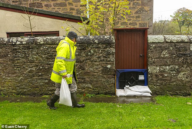 BRECHIN: Some 360 homes in the Scottish town will be evacuated. Here, Local resident Christopher McGuire places sand bags at houses as Storm Babet closes in