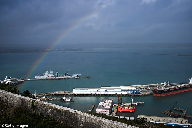 A rainbow appears over the Bibby Stockholm in Portland Port with ominous grey skies above