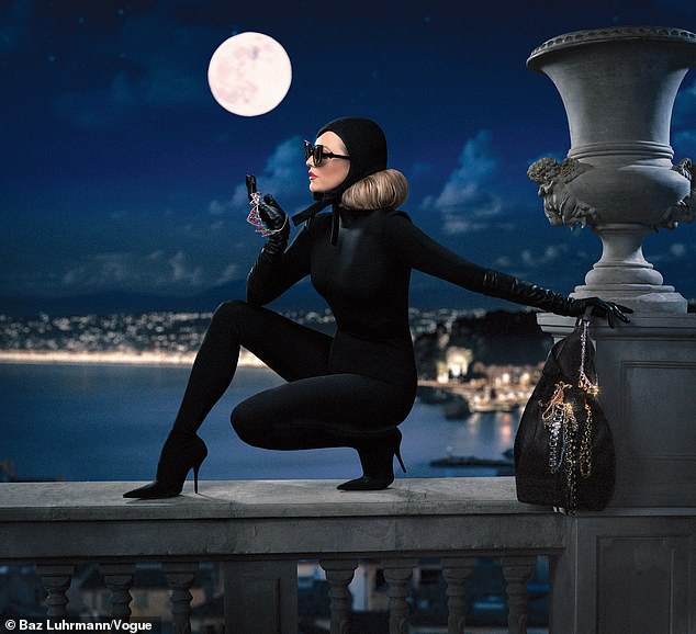 She wears a black Balenciaga pantabodysuit, hat by Hood London, and sunglasses as she perches on a railing overlooking the city at night with Elizabeth Taylor's stolen ruby necklace in her hand