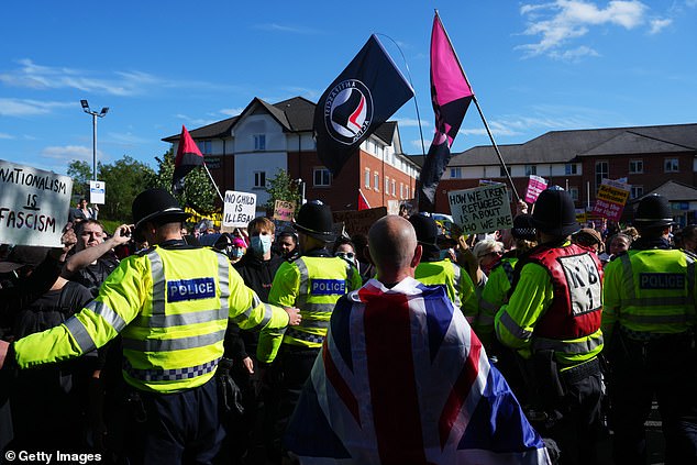 Police stand in a line in front of protesters during a rally on August 9 in Crawley, England