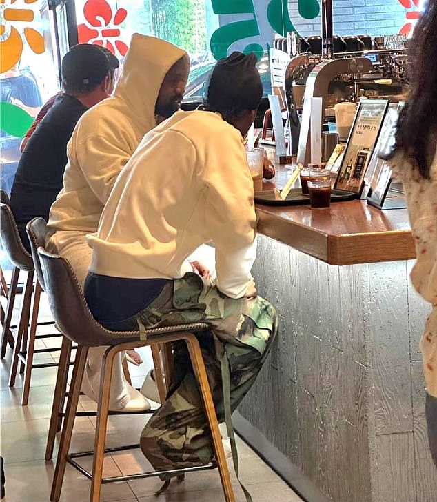 Here the rapper wore a white hoodie with gray sweatpants as she sat at a bar with a pal