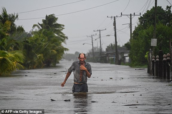 TOPSHOT - A residents of the coastal town of Guanimar in Artemisa province, southwest of Havana, wade trough a flooded street after the passage of Hurricane Helene on September 25, 2024. Tropical Storm Helene became a hurricane mid-morning in the Gulf of Mexico. "Life-threatening storm surge, hurricane-force winds, rainfall and flooding are expected across much of Florida and the southeastern United States," the Miami-based National Hurricane Center (NHC) said in its latest bulletin. (Photo by YAMIL LAGE / AFP) (Photo by YAMIL LAGE/AFP via Getty Images)