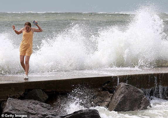 ST PETE BEACH, FLORIDA - SEPTEMBER 26: Callie Padgett runs from a wave crashing ashore from the Gulf of Mexico as Hurricane Helene passes offshore on September 26, 2024 in St. Pete Beach, Florida. Later today, Helene is forecast to become a major hurricane, bringing the potential for deadly storm surges, flooding rain, and destructive hurricane-force winds along parts of the Florida West Coast. (Photo by Joe Raedle/Getty Images)