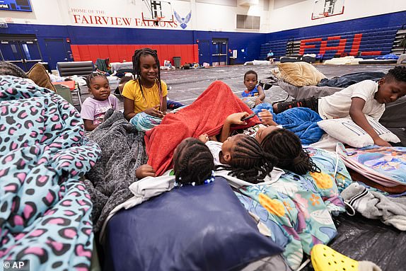 The grandchildren and great grandchildren of Vera Kelly, of Tallahassee, sit together after evacuating to a hurricane shelter at Fairview Middle School, ahead of Hurricane Helene, expected to make landfall here today, in Leon County, Fla., Thursday, Sept. 26, 2024. (AP Photo/Gerald Herbert)