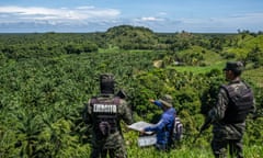 A man and two soldiers looking out over a national park containing an illegal oil palm plantation in Honduras.