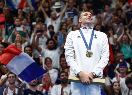 Gold medallist Leon Marchand of France celebrates on the podium after winning and establishing Olympic record in the men’s 200m breaststroke.