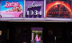 FILE - A patron buys a movie ticket underneath a marquee featuring the films "Barbie" and "Oppenheimer" at the Los Feliz Theatre, on July 28, 2023, in Los Angeles. The Japanese distributor of Warner Bros. movie “Barbie” has apologized over its U.S. parent company’s positive reaction to social media postings of “Barbenheimer” memes playing with Barbie and images of atomic bombing mushroom clouds, which triggered criticisms in Japan. Warner’s Barbie, a live-action film about the world-famous doll and Universal’s Oppenheimer, a biography of “father of the atomic bomb” Robert Oppenheimer, who helped develop the weapon, were both released on July 21 in United States. (AP Photo/Chris Pizzello, File)