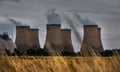 view of the site showing six huge smoking chimneys from a field in the foreground