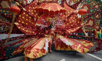 A person wearing a huge and elaborate red/orange costume with golden highlights