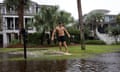 A man slides on flood water in a residential street