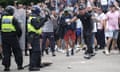 Riot police face men who are aggressively gesturing towards them