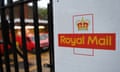 A Royal Mail logo on a black gate with bars and a red van in the background