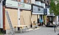 Van with workmen and ladders boarding up shop windows