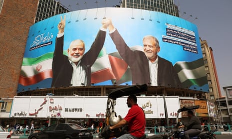 Iranians drive past a billboard depicting the president, Masoud Pezeshkian (R), and late the Hamas leader Ismail Haniyeh, at Valiasr Square in Tehran