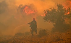 A firefighter runs away from a wildfire near Athens, Greece, in 2023.