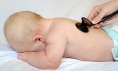 A baby has their heart checked by a doctor with a stethoscope.