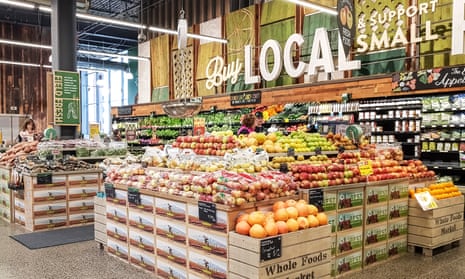 Fruit and veg piled high in a shop with a sign on the wall saying "Buy local and support small".