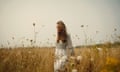 Kate walking through a wheat field in a floaty dress.